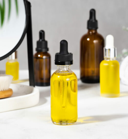 Oils, bath brush, towel and mirror on the cosmetic table in the bathroom. A set of organic cosmetics in glass bottles with dropper for skin and hair care. The concept of home care in the bathroom.